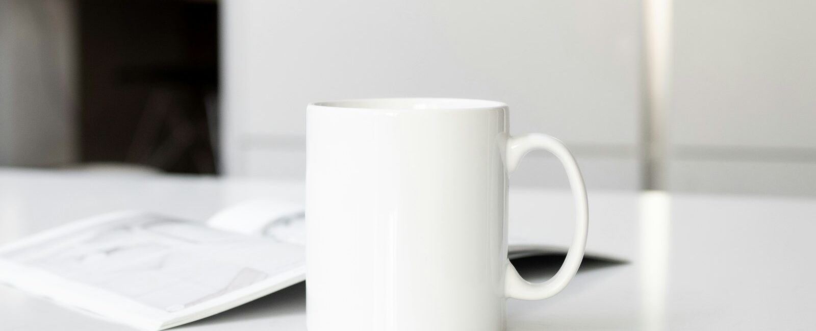 a white coffee cup sitting on top of a white table